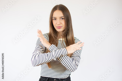 Beautiful girl wearing striped t-shirt against white wall Rejection expression crossing arms doing negative sign, angry face