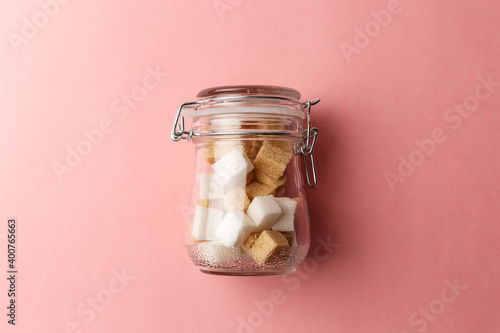 Billede på lærred Jar with white sugar cubes and brown cane sugar lump on pastel pink background