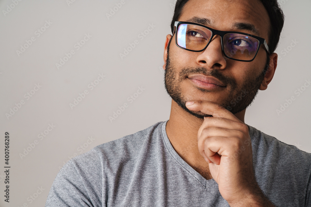 Asian unshaven man looking at copyspace and touching his chin Asian unshaven man looking at copyspace and touching his chin