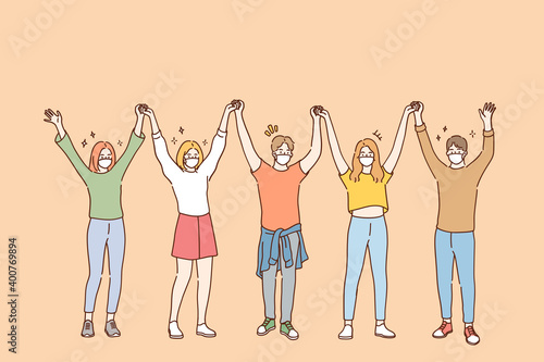 Friendship and having fun during COVID-19 pandemic concept. Group of young positive friends in protective medical face masks standing and holding raised hands in team during pandemic illustration 