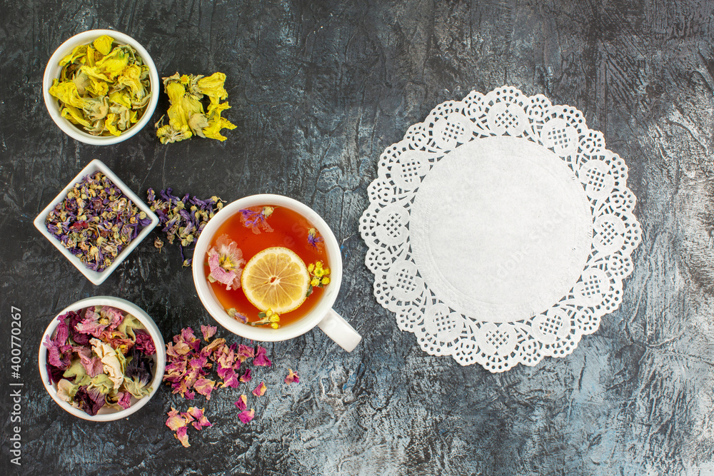 top view of a cup of herbal tea with bowls of dry flowers and lace on grey background top view of a cup of herbal tea with bowls of dry flowers and lace on grey background