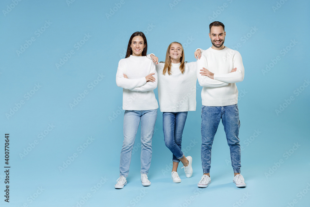 Full length of funny young happy parents mom dad with child kid daughter teen girl in white sweaters holding hands crossed isolated on blue background studio portrait. Family day parenthood concept. Full length of funny young happy parents mom dad with child kid daughter teen girl in white sweaters holding hands crossed isolated on blue background studio portrait. Family day parenthood concept.