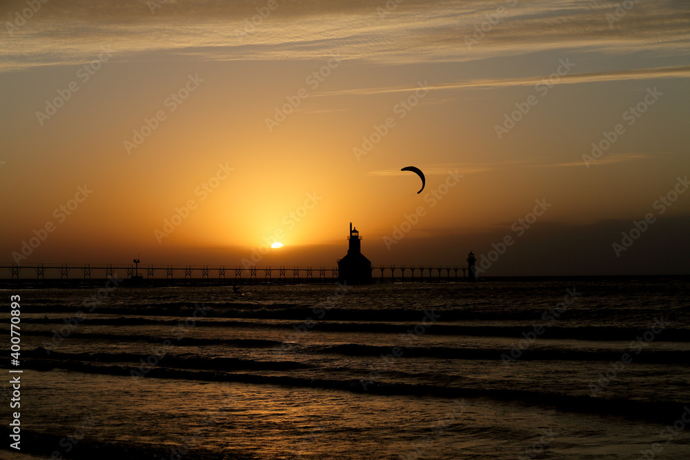 Kite boarder at sunset by a lighthouse