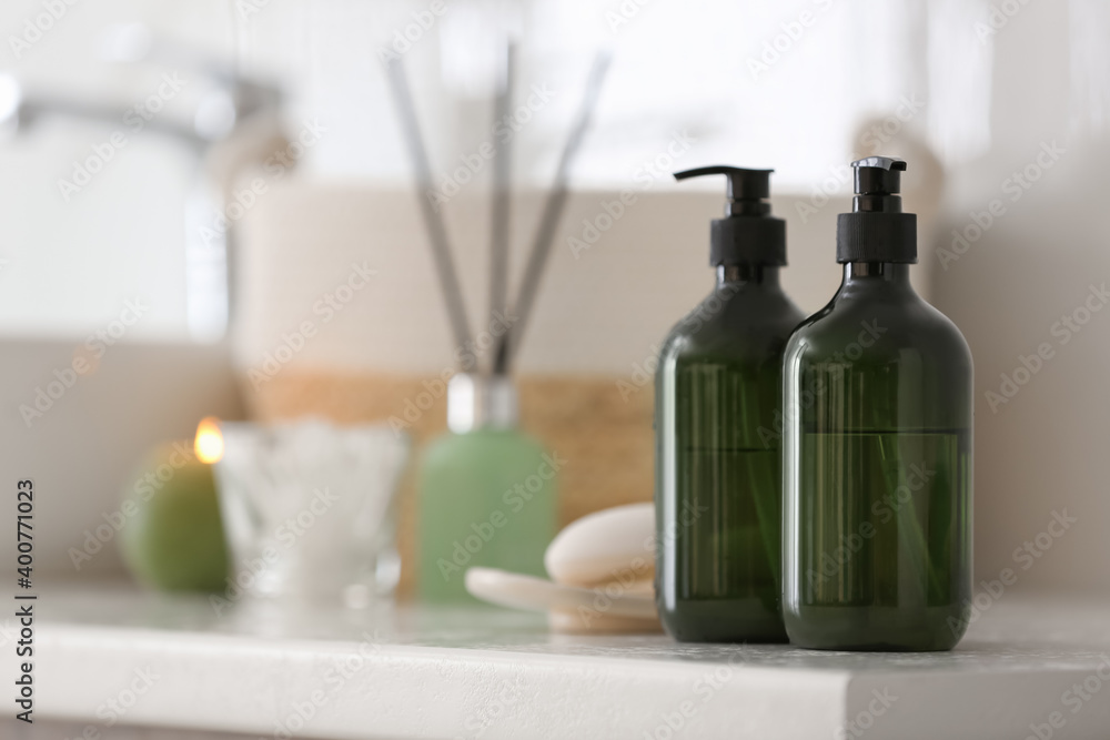 Green soap dispensers on countertop near sink in bathroom. Space for text