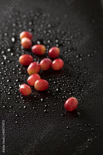Top view closeup of red grapes isolated on a black background with water drops