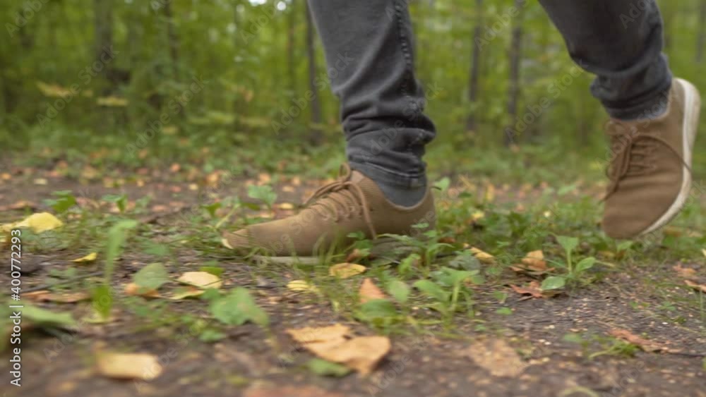 Man Walks along the Forest. Tourist in Boots Going along the Road on the Background a Beautiful Landscape. Travel Concept Active People on the Way to Victory Move Forward Close Up. Man Walks along the Forest. Tourist in Boots Going along the Road on the Background a Beautiful Landscape. Travel Concept Active People on the Way to Victory Move Forward Close Up.