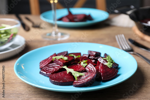 Roasted beetroot slices with arugula on wooden table, closeup