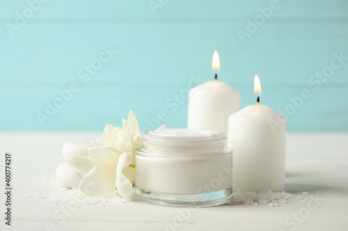 Spa composition with cream  candles and flowers on white table