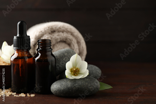 Composition with spa stones and aroma oil on wooden table, space for text