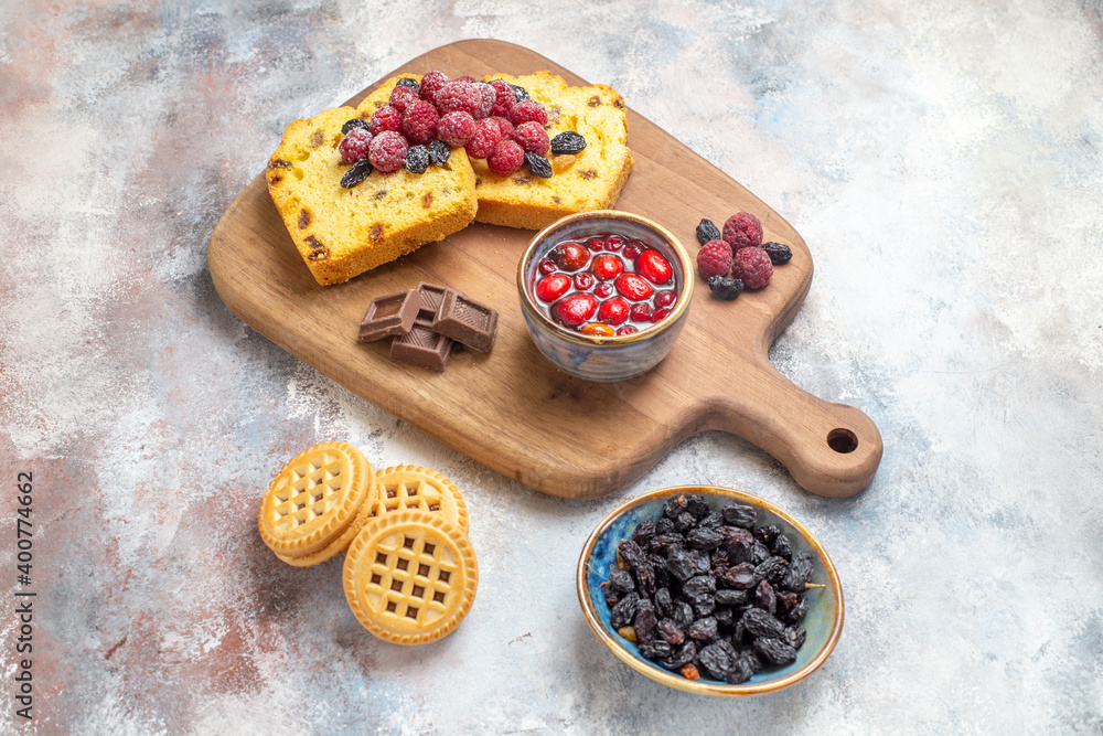 top view raisin cake slices chocolate and cornel jam bowl on cutting board biscuits and a bowl of raisins on marble ground with copy space top view raisin cake slices chocolate and cornel jam bowl on cutting board biscuits and a bowl of raisins on marble ground with copy space