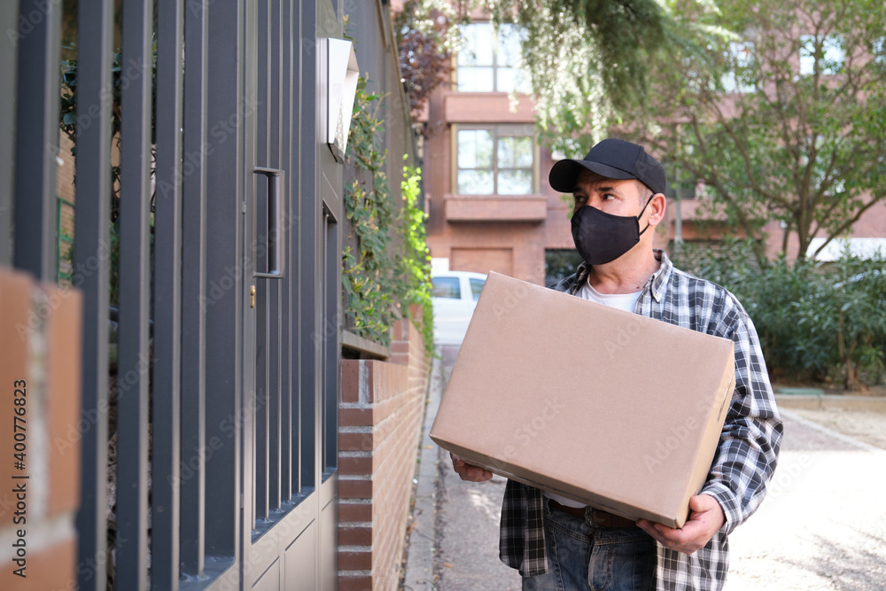 Delivery senior man waiting at the door holding a package. Delivery service under quarantine, disease outbreak, coronavirus covid-19 pandemic conditions. Delivery senior man waiting at the door holding a package. Delivery service under quarantine, disease outbreak, coronavirus covid-19 pandemic conditions.