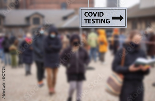 People waiting in line queued up for health screening for Coronavirus Covid-19 testing or vaccine at city test center. Blurred image with selective focus. © Ole