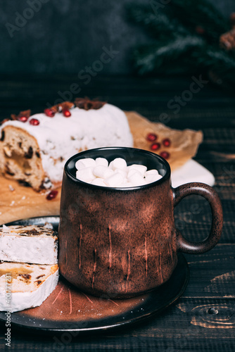 Christmas fruit cake with sugar powder on marble board. Hot chocolate in a ceramic mug. Wooden table and copy space for your text