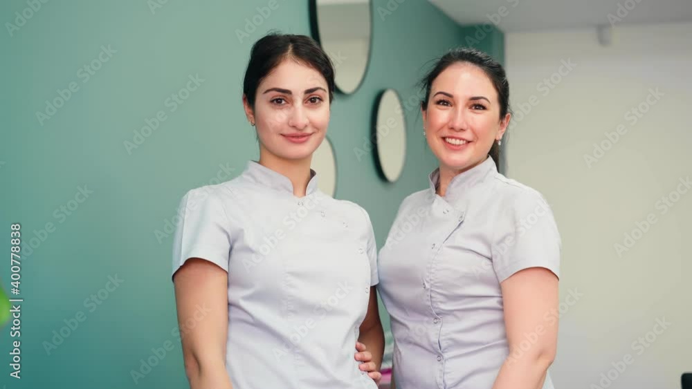 Two beautiful nurses take off medical masks from their faces and smile for the camera. Healthcare and Medicine Concept. High quality 4k footage Two beautiful nurses take off medical masks from their faces and smile for the camera. Healthcare and Medicine Concept. High quality 4k footage