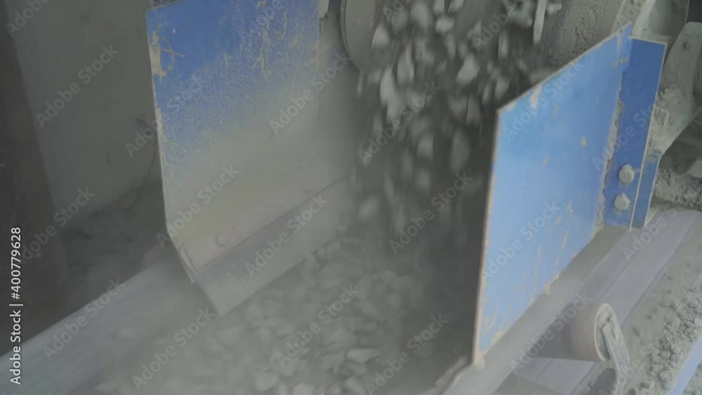 Crushed stone is dumped from a conveyor onto a moving belt. running belt Crushed stone is dumped from a conveyor onto a moving belt. running belt