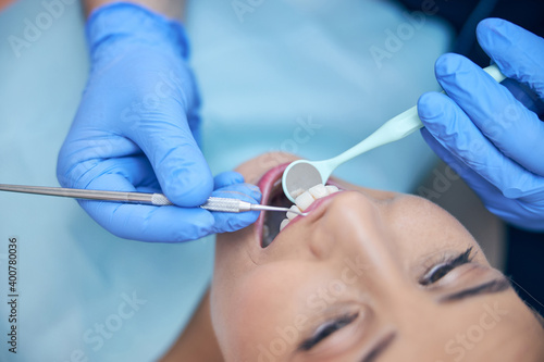 Smiling young woman during procedures in dental clinic