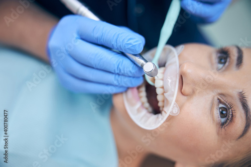 Dentist treating young beautiful female in office