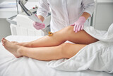 Dermatologist removing unwanted hair on female legs