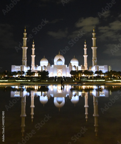 Spiegelung der nächtlich beleuchteten Scheich-Zayid-Moschee auf blanker Wasseroberfläche