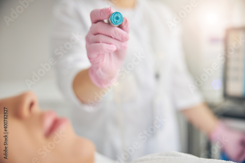 Female cosmetologist treating her young patient skin