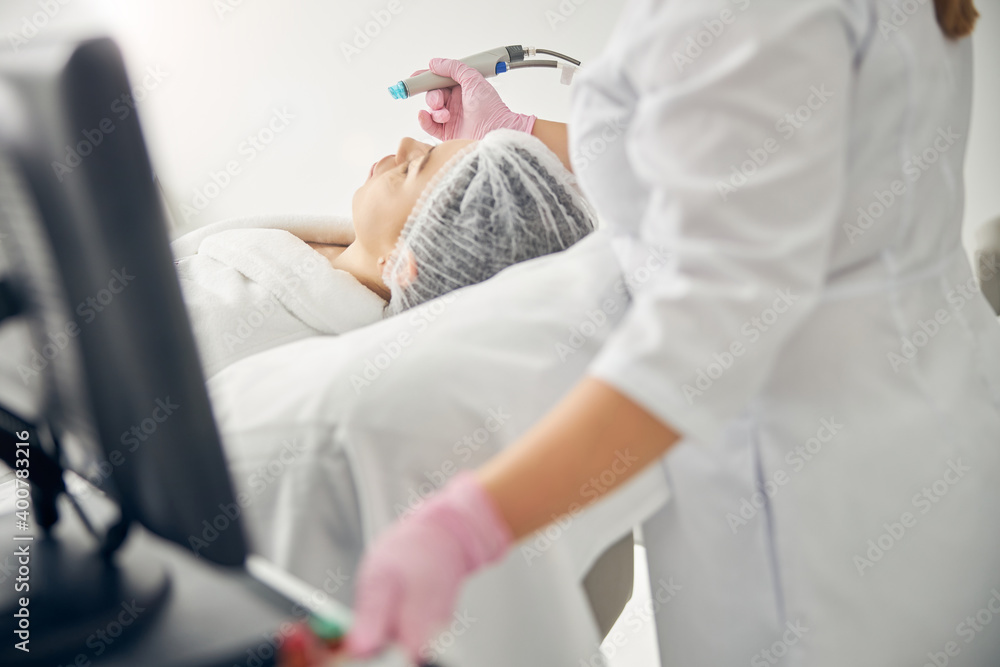 Female doctor treating a woman using a beauty machine Female doctor treating a woman using a beauty machine