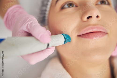 Professional female cosmetologist performing a hydrodermabrasion treatment