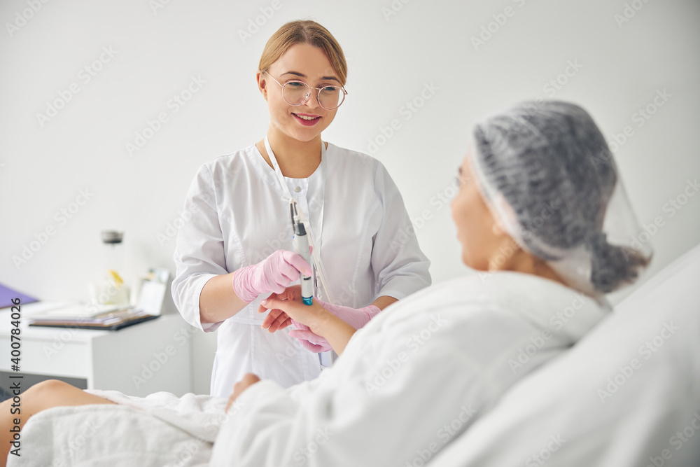 Friendly young dermatologist conducting a cosmetic procedure Friendly young dermatologist conducting a cosmetic procedure