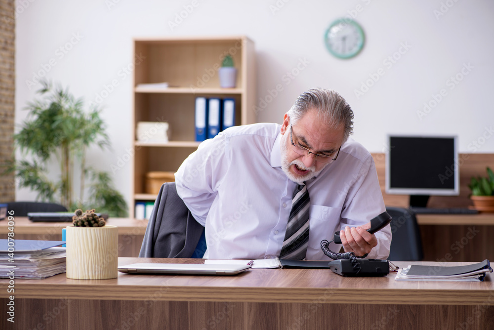 Old male employee suffering from radiculitis at workplace Old male employee suffering from radiculitis at workplace