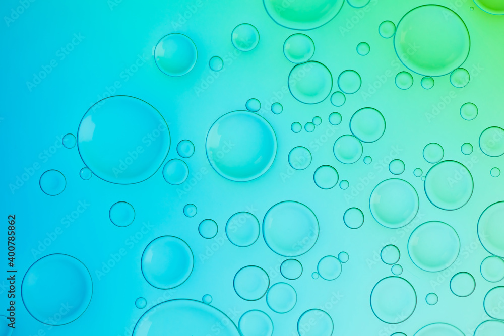 Creative neon background with drops. Glowing abstract backdrop with vibrant gradients on bubbles. Blue, turquoise and green white overflowing colors