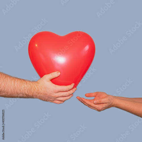 The guy gives the girl a red volumetric heart on a blue background, isolate