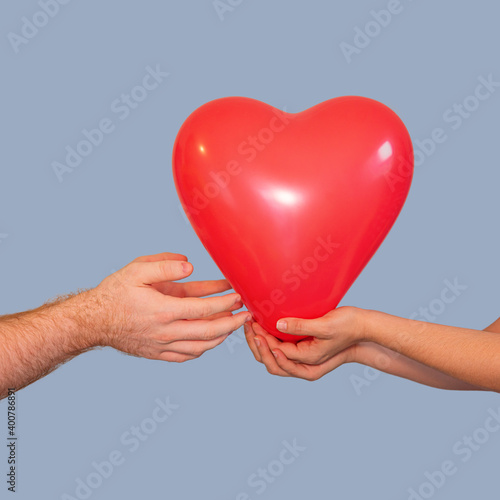 Girl gives a guy a red volumetric heart on a blue background, isolate