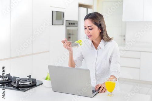 Young woman eating salad during work from home