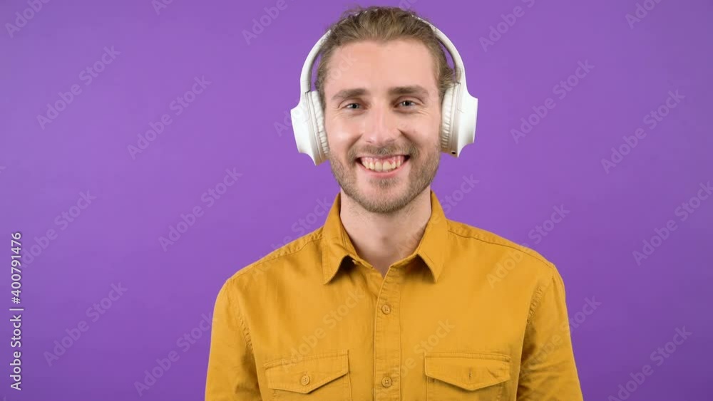 portrait of a long-haired man in large white headphones. smiling man isolated purple screen 4K portrait of a long-haired man in large white headphones. smiling man isolated purple screen 4K