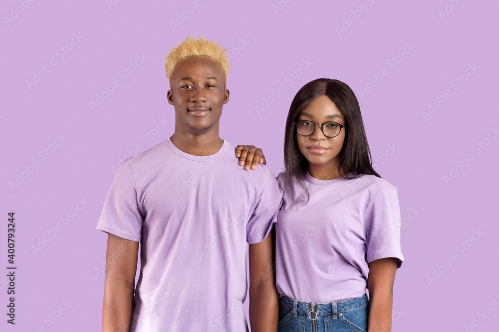 Portrait of handsome black man and his girlfriend in glasses posing and looking at camera over violet studio background Portrait of handsome black man and his girlfriend in glasses posing and looking at camera over violet studio background