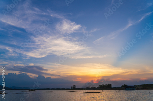 The sun shines through the clouds in the evening on a lake in Thailand.