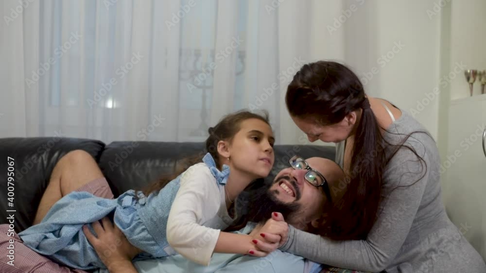 Father joins in the sofa with the family and start tickling everybody. Young carefree parents and little girl laugh play cuddling at home enjoy funny game on couch. Father joins in the sofa with the family and start tickling everybody. Young carefree parents and little girl laugh play cuddling at home enjoy funny game on couch.