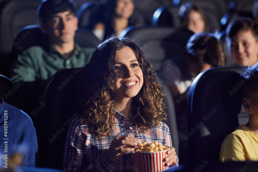 Young laughing woman eating popcorn in cinema.