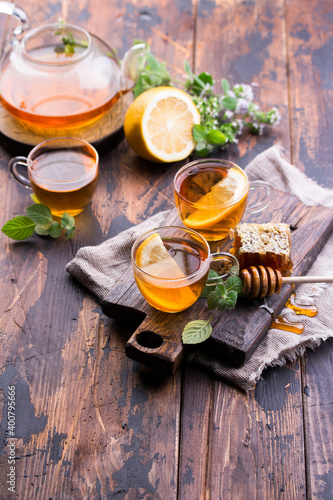 Transparent cup of tea with honey and mint on wooden background