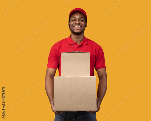 Black delivery man holding pile of boxes