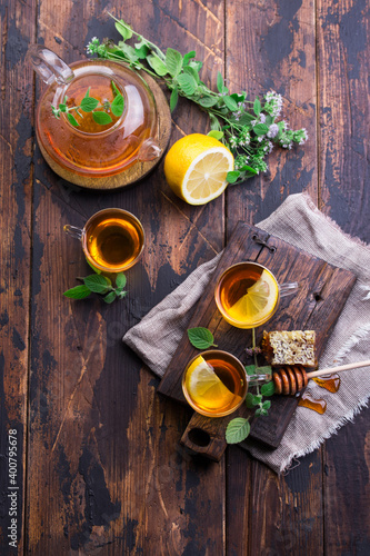 Transparent cup of tea with honey and mint on wooden background
