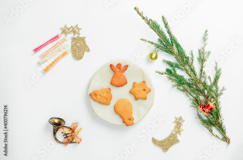 Gingerbread cookies on plate with fir branch and New Years toys on the table. The tradition of baking gingerbread cookies for New Year and Christmas.
