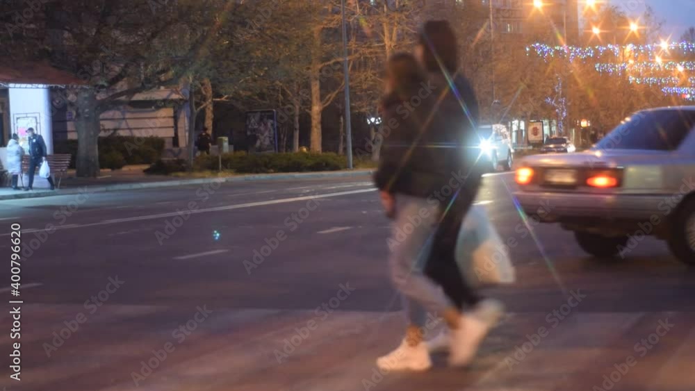 Night city with passing cars and lines from car headlights and lanterns, people walking in the evening city Night city with passing cars and lines from car headlights and lanterns, people walking in the evening city