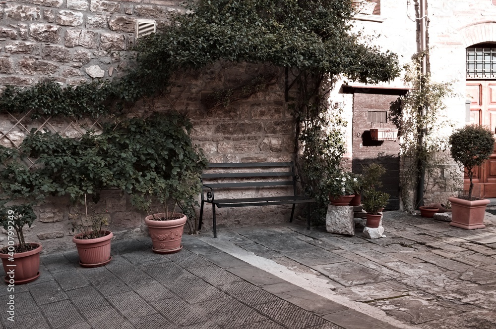 Fototapeta premium A courtyard with plant and clay pots of a stone house in a medieval italian village (Gubbio, Umbria, Italy)