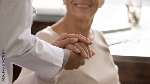 Close up view of supportive female nurse comfort caress touch hold mature patient hand. Woman doctor support take care of senior client at consultation, show empathy and love. Healthcare concept.