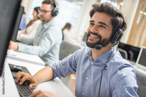 Young handsome technical support dispatcher working in call center. photo