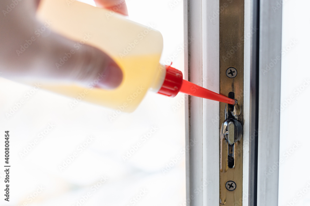 Ταπετσαρία hand lubricates window frame mechanism with oil from oiler close up