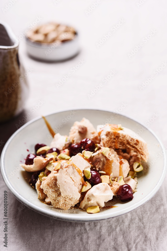 Not traditional Eton mess. Meringue, pistachio, cherry and caramel sauce dessert. Selective focus Not traditional Eton mess. Meringue, pistachio, cherry and caramel sauce dessert. Selective focus