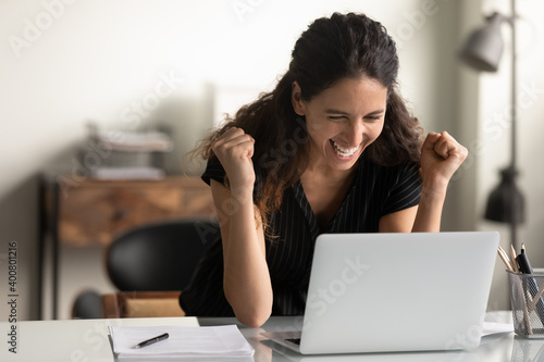 Overjoyed young Caucasian woman look at laptop screen feel euphoric win lottery on gadget online. Happy millennial female triumph reading good unbelievable news on computer. Luck, reward concept.