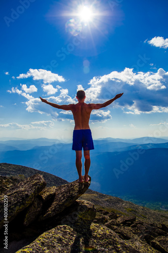 man stands on top of a mountain with open hand © efimenkoalex