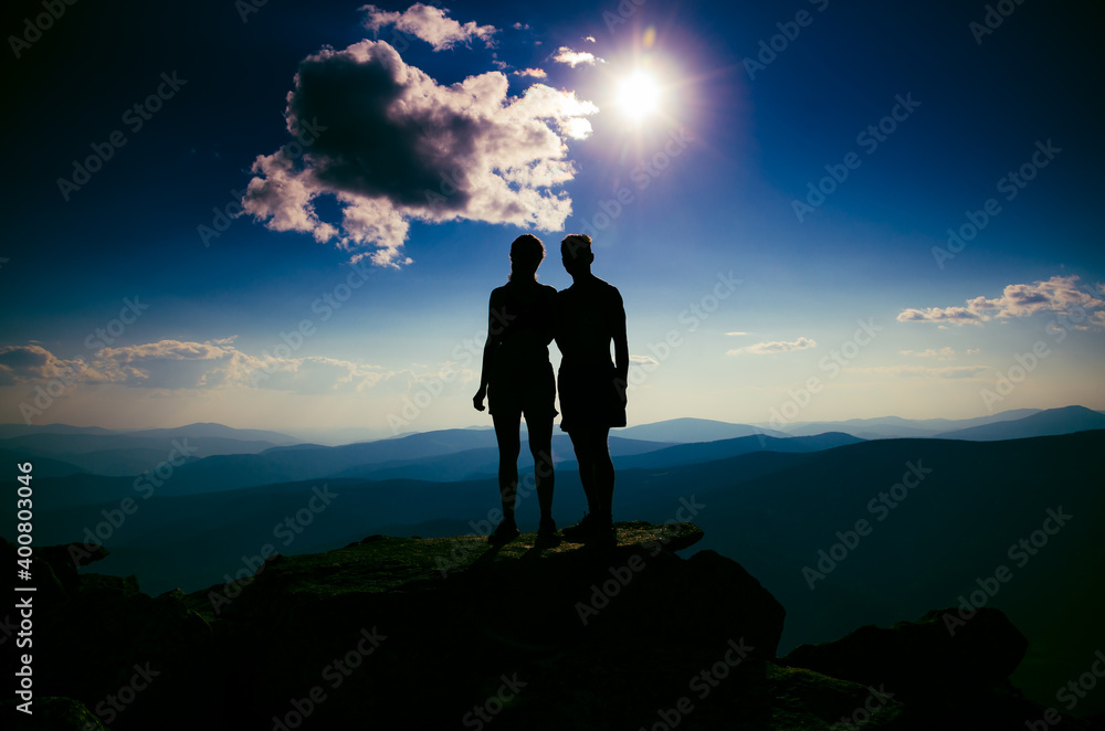 a loving couple holding hands at the top of a mountain.